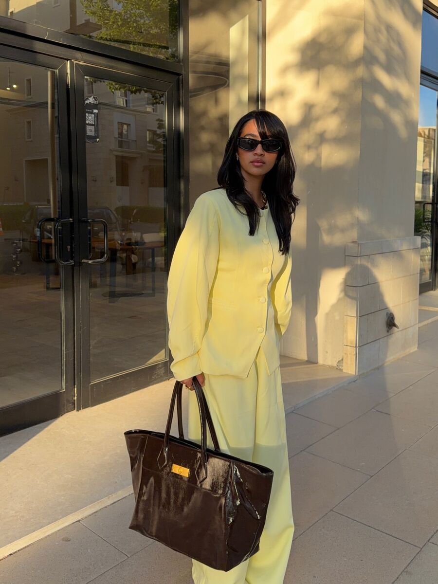A woman in a butter yellow jacket and trousers in evening light