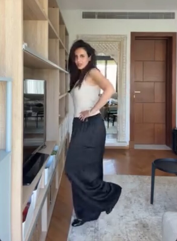 A woman in a white top and long black trousers at home