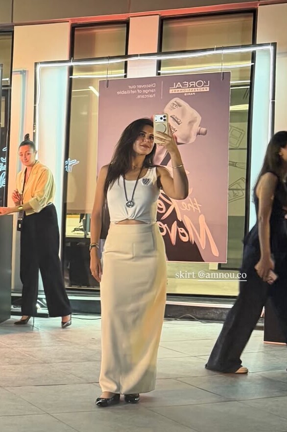 A woman in a long cream skirt and white top at an evening event
