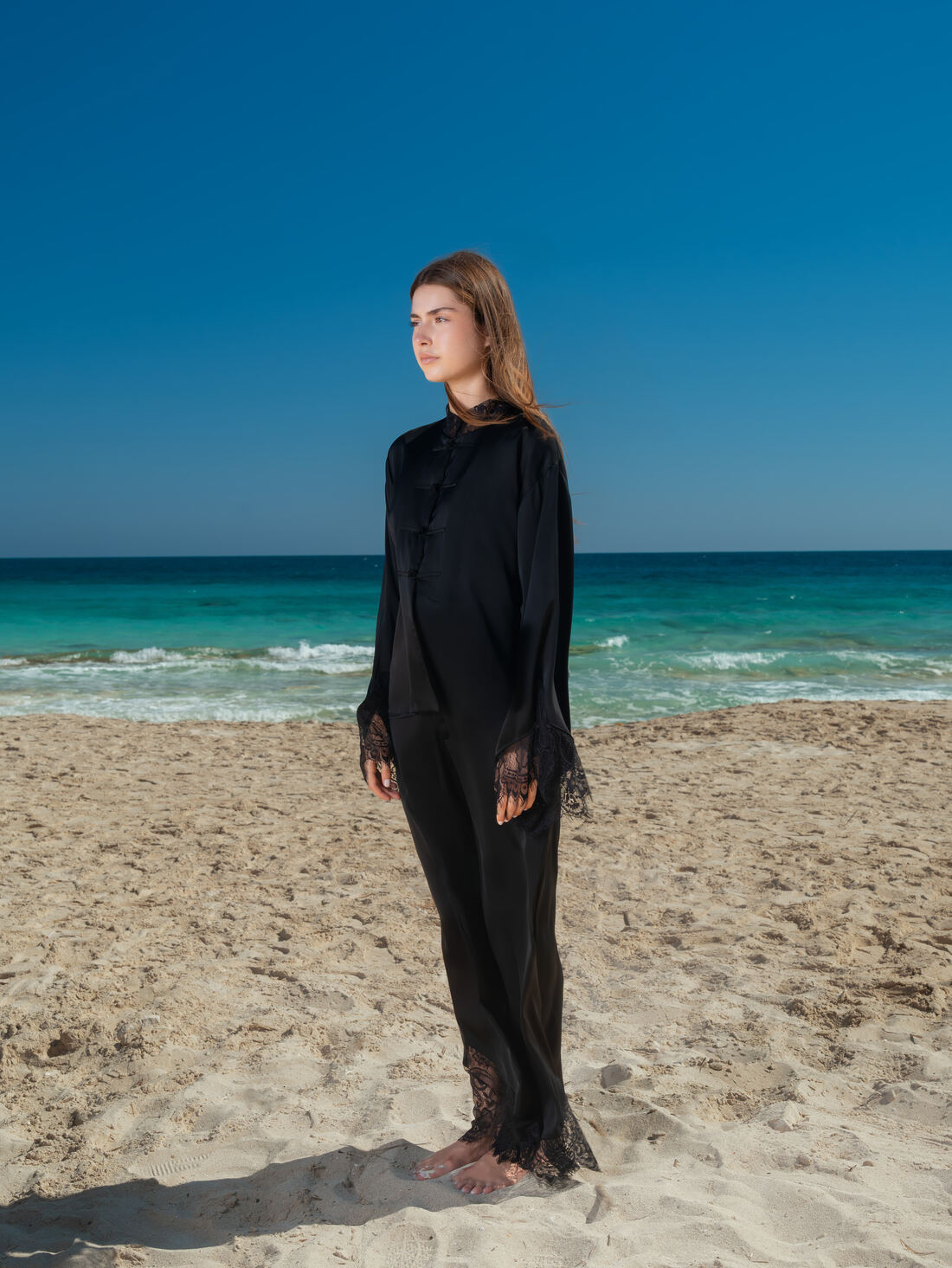 A woman standing on the shore, dressed in black