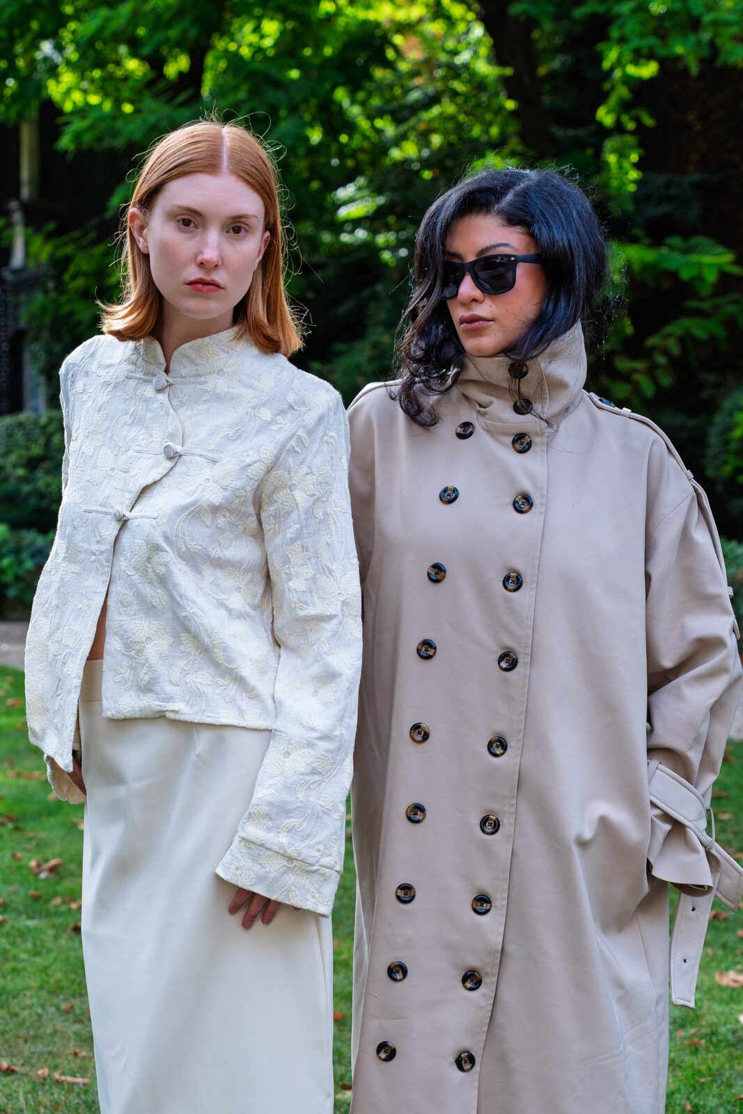 Two women in a Paris garden, one in the Linen Embroidered Jacket, one in a stone-coloured double-breasted coat
